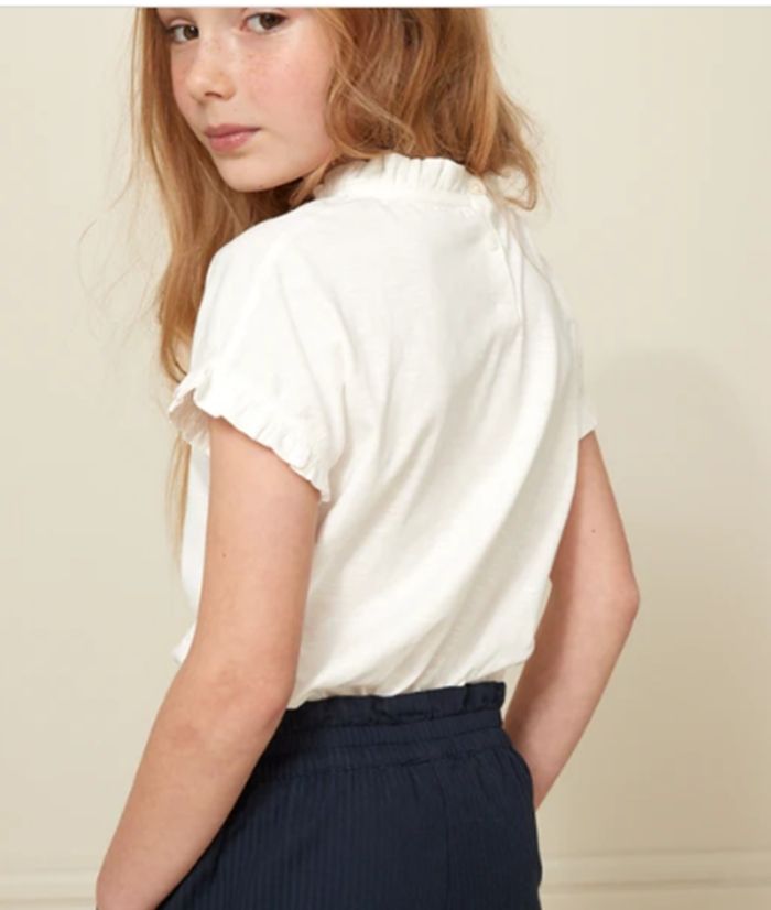 100% organic cotton<br>
• Small button placket at back<br>
• Ruffled finish
		
	
	
		
		
	
			
	
